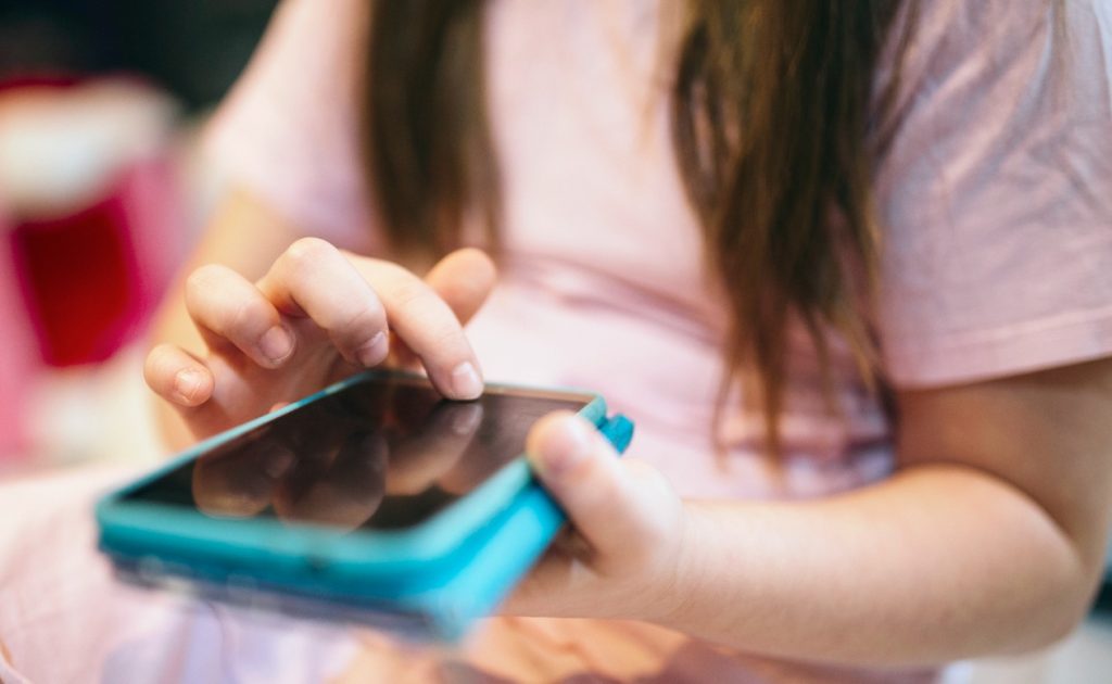 Mãos de criança manipulando smartphone