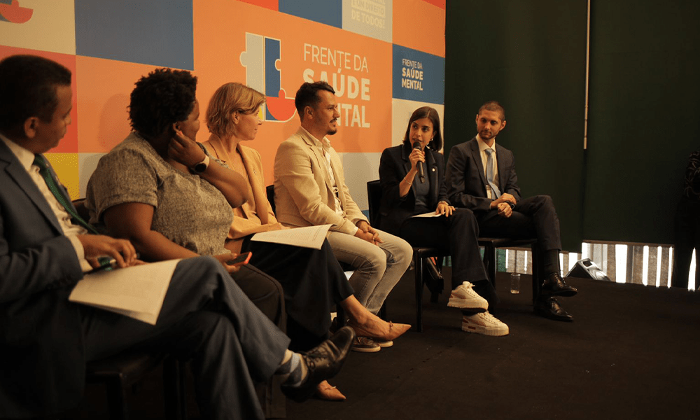 Painel de debate com participantes sentados em poltronas durante evento da Frente Parlamentar Mista de Saúde Mental.